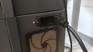 The power switch on the machine is located next to the machine's power cord.